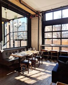 an empty restaurant with tables and chairs in front of large windows that look out onto the city