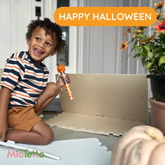 a young boy sitting on the floor holding a candy lollipop in his hand