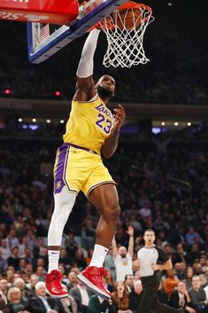 a basketball player dunking the ball in front of an audience at a game,