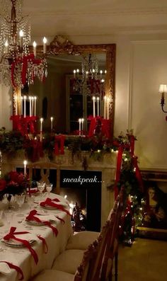 a dining room table set for christmas dinner with red ribbon on the table and candles in the fireplace