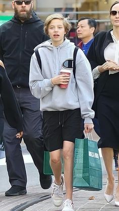 a group of people walking down the street with shopping bags and coffee in their hands