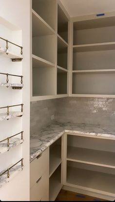 an empty pantry with marble counter tops and shelves