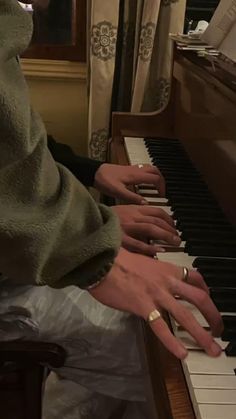 a person sitting at a piano with their hands on the keys and wearing a hood