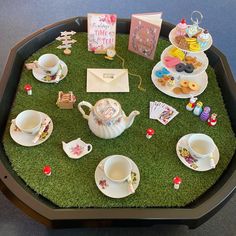 there is a tray with tea and other items on the green carpeted table top