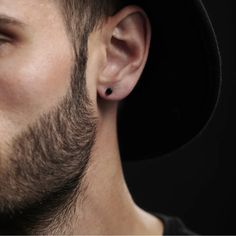 a man wearing a black hat and ear piercings