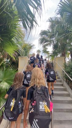 the girls are walking down the stairs in their black sports uniforms and carrying backpacks