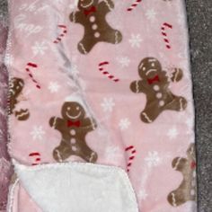 a pink blanket with gingerbreads and candy canes on it's side