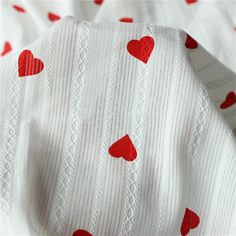 a white sweater with red hearts on it is laying on top of a bed sheet