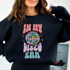 This In My Disco Era retro groovy crewneck sweatshirt with disco ball will let everyone know you love to dance the night away disco style!! It's the perfect for those who want to share their love for disco and let the world know you love to dance! Ideal for any situation, a unisex heavy blend crewneck sweatshirt is pure comfort. These garments are made from polyester and cotton. This combination helps designs come out looking fresh and beautiful. The collar is ribbed knit, so it retains its shap Disco Style Crew Neck Tops With Letter Print, 70s Disco Dance, Ladies Sweatshirt, Disco Style, Skate Party, Disco Era, Disco Dance, 70s Disco, Retro Groovy