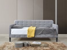 a gray couch sitting on top of a shaggy rug next to a white and yellow blanket