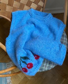 a blue sweater sitting on top of a wooden chair next to a wicker basket