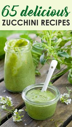 two jars filled with green smoothie sitting on top of a wooden table next to flowers