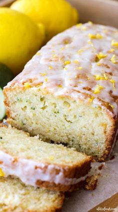 a loaf of lemon zucchini bread next to two lemons and a cucumber