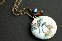 A handmade locket necklace created with a 32mm bronze locket with a hand-screened depiction of a colorful bird perched on a bike. The locket is then joined with a delicate fresh water pearl charm in cobalt blue, and a rich brown glass teardrop wrapped by hand in bronze wire. [See additional listing pictures for a view of the back and inside of the locket.] Add your own personal photo inside any locket in my shop with this listing: https://www.etsy.com/TheTeardropShop/listing/568217066 There are Handmade Brass Locket Necklace For Vintage Collection, Handmade Round Brass Locket Necklace, Handmade Adjustable Antique Locket Necklace, Handmade Antique Adjustable Locket Necklace, Antique Gold Retro Jewelry For Gifts, Handmade Vintage Locket Necklace Adjustable, Handmade Adjustable Vintage Locket Necklace, Handmade Vintage Adjustable Locket Necklace, Handmade Brass Medallion Locket Necklace