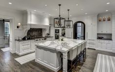 a large kitchen with white cabinets and marble counter tops, an island in the middle