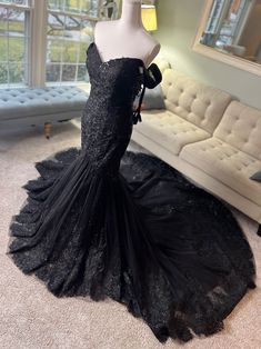 a mannequin in a black dress is standing on the floor next to a couch