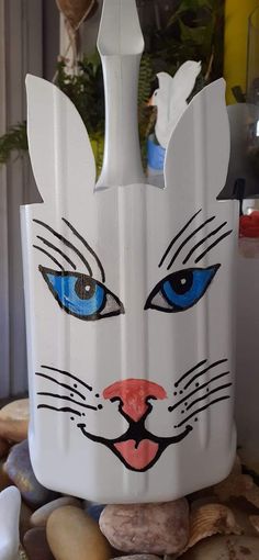 a white vase with blue eyes and a cat's head painted on it