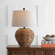 a table lamp sitting on top of a wooden dresser next to a bowl and book