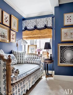 a living room with blue walls and pictures on the wall above the loveseat