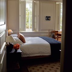 a bed sitting in a bedroom next to a window with white walls and wooden floors