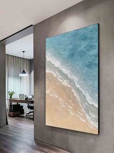 a large painting hanging on the wall above a wooden floor in front of a living room