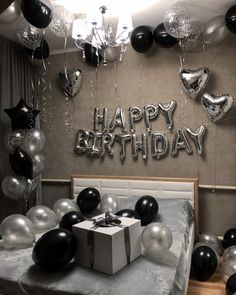 a bedroom decorated with balloons, presents and black and silver decorations for a birthday party