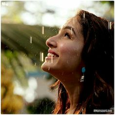 a woman is smiling while standing in the rain with her head tilted to the side