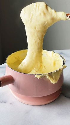 a person is mixing some food in a pink bowl with a wooden spoon on the table