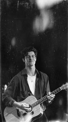 a black and white photo of a man playing an acoustic guitar