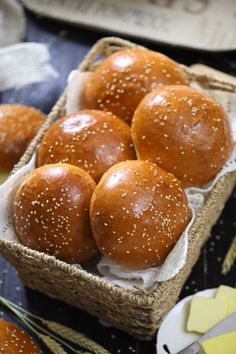 several buns in a basket on a table with cheese and breadsticks next to them