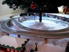 a toy train set is shown in front of a christmas tree