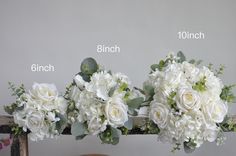 three bouquets of white flowers sitting on top of a wooden table next to each other