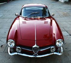 an old red car is parked on the street