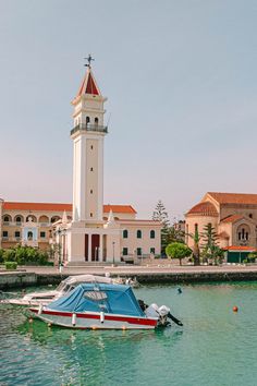 there is a boat in the water near a building with a clock tower on it