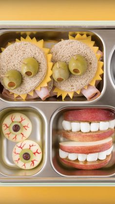 an open lunch box with sandwiches, fruit and vegetables in it's trays