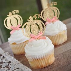 three cupcakes with white frosting and gold decorations