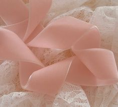 a pink bow on top of white lace