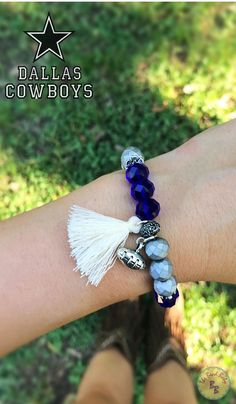 a woman's arm wearing a bracelet with beads and tassels on it