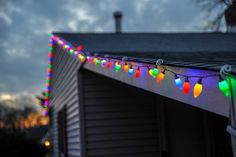 christmas lights are hanging from the roof of a house