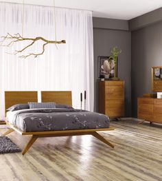 a bed sitting on top of a hard wood floor next to a dresser and mirror