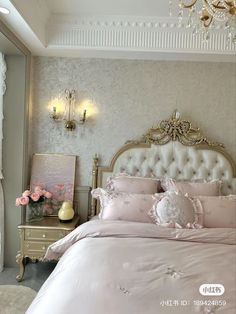 a bedroom with a bed, chandelier and flowers on the nightstands in front of it