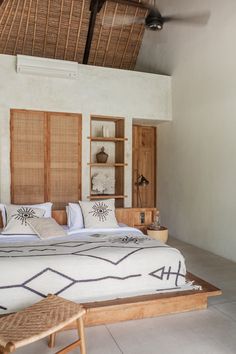 a large bed sitting inside of a bedroom on top of a white floor covered in pillows