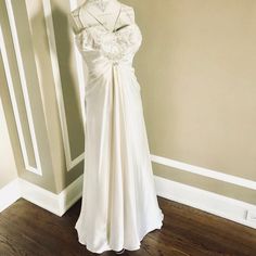 a white wedding dress hanging on a wall next to a mannequin's head