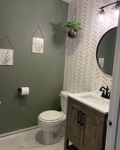 a white toilet sitting next to a wooden cabinet in a bathroom under a round mirror