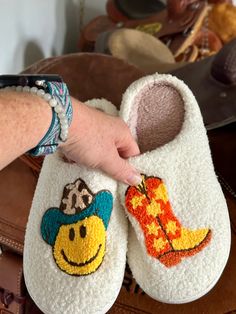 Here’s some fun slippers for the Cowgirls and Cowgirls at heart! These comfy slippers feature a Smiley Face Cowboy and Cowboy Boots. They're incredibly comfy, extra cozy, and feature a rubber bottom ideal for indoor and outdoor wear.Very limited quantity - don't miss out on these fun slippers! Sizing Information:This item is based on women's sizing, and men should size up for the best fit. Size Chart: 6/7: Length 9" 7/8: Length 9 3/4" 8/9: Length 10" 9/10: Length 10 1/2" 11/12: Length 10 3/4" Be Fun Multicolor Non-slip Slippers, Playful Indoor Slippers With Round Toe, Cute Round Toe Slippers For Leisure, Fun Round Toe Winter Slippers, Fun Round Toe Slippers For Winter, Fun Slippers With Soft Sole And Round Toe, Cute Multicolor Slippers With Round Toe, Comfy Slippers With Soft Sole And Round Toe, Super Soft Comfy Slippers With Round Toe