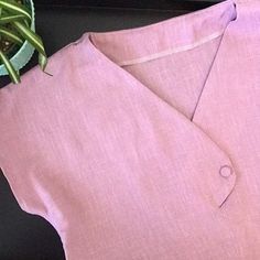 a close up of a pink shirt with a plant in the background