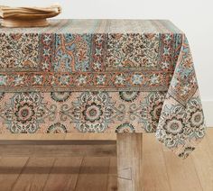 a table with a blue and orange paisley design on it, sitting on a wooden floor