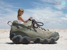 a woman sitting on top of a shoe in the sand