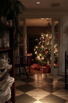 a christmas tree is lit up in the corner of a room with many plates and cups