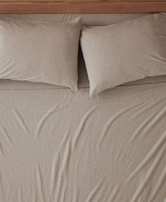 an unmade bed with two pillows on it